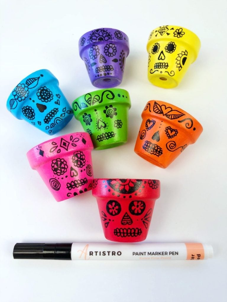 Drawing sugar skulls on mini flower pots with a paint marker